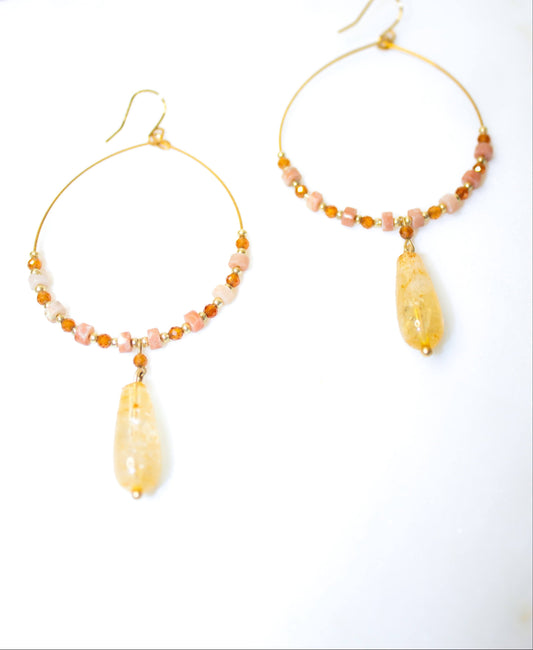 Pair of hoop earrings with beads and teardrop-shaped stones on a white background