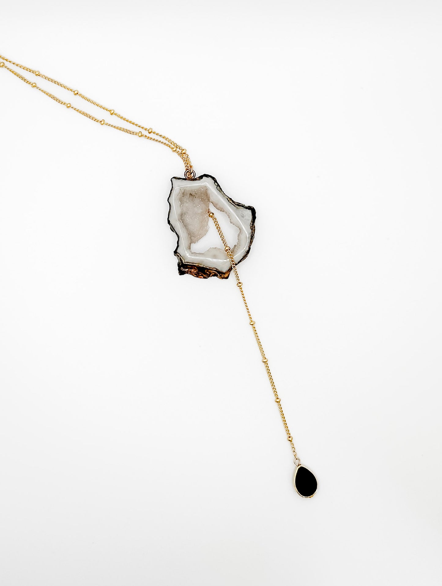 Necklace with a crystal pendant and black teardrop charm on a white background