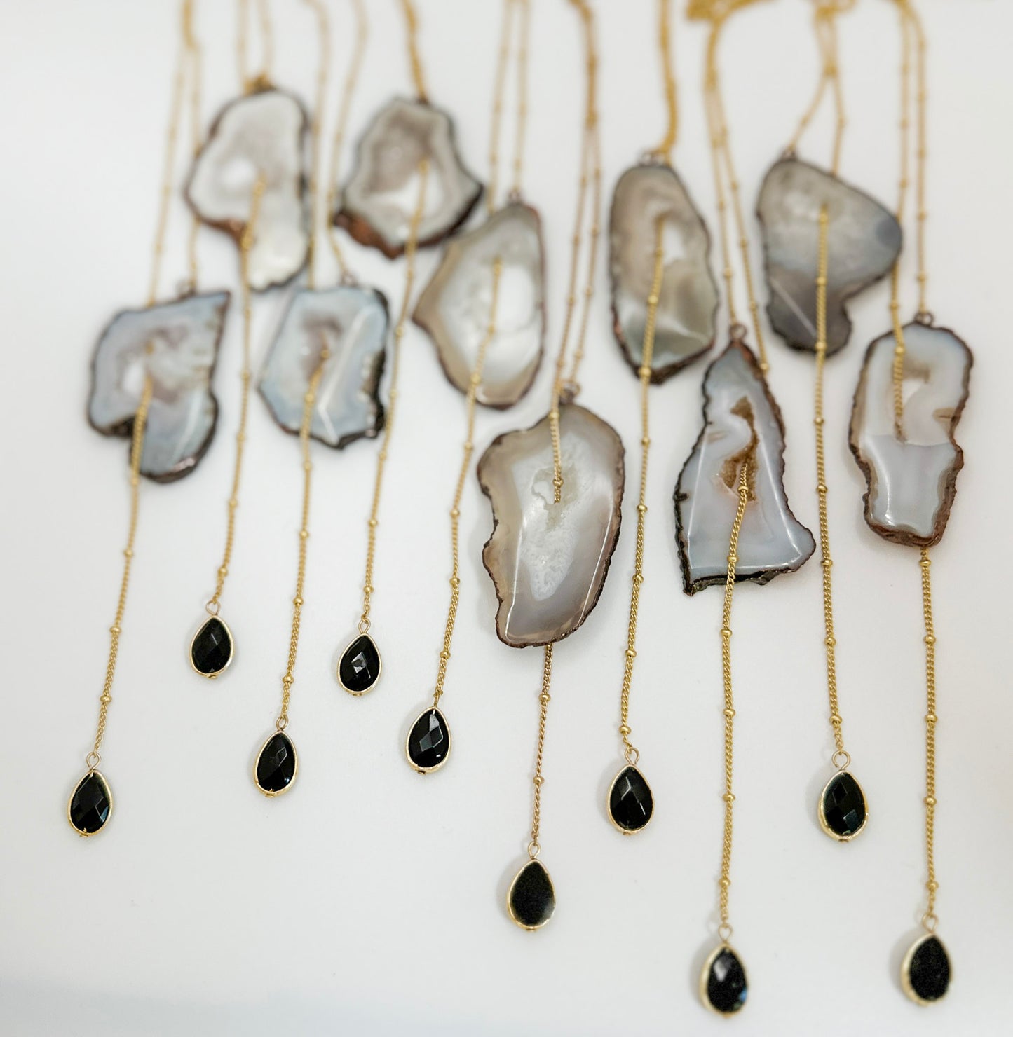 Necklaces with agate slices and black teardrop pendants on a white background