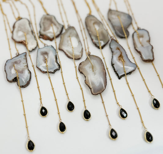 Necklaces with agate stones and black teardrop pendants on a white background
