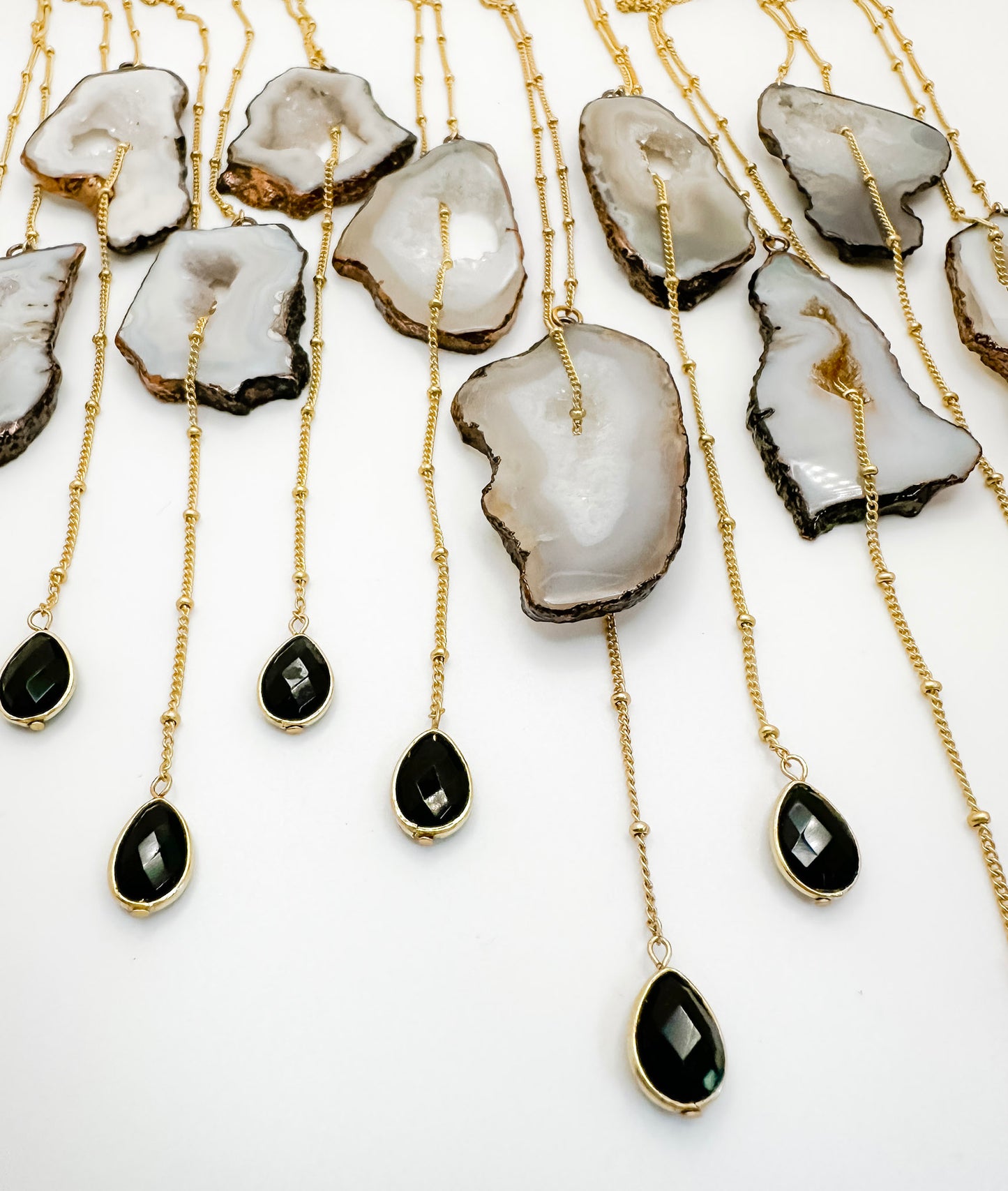 Necklaces with agate stones and black teardrop pendants on gold chains.