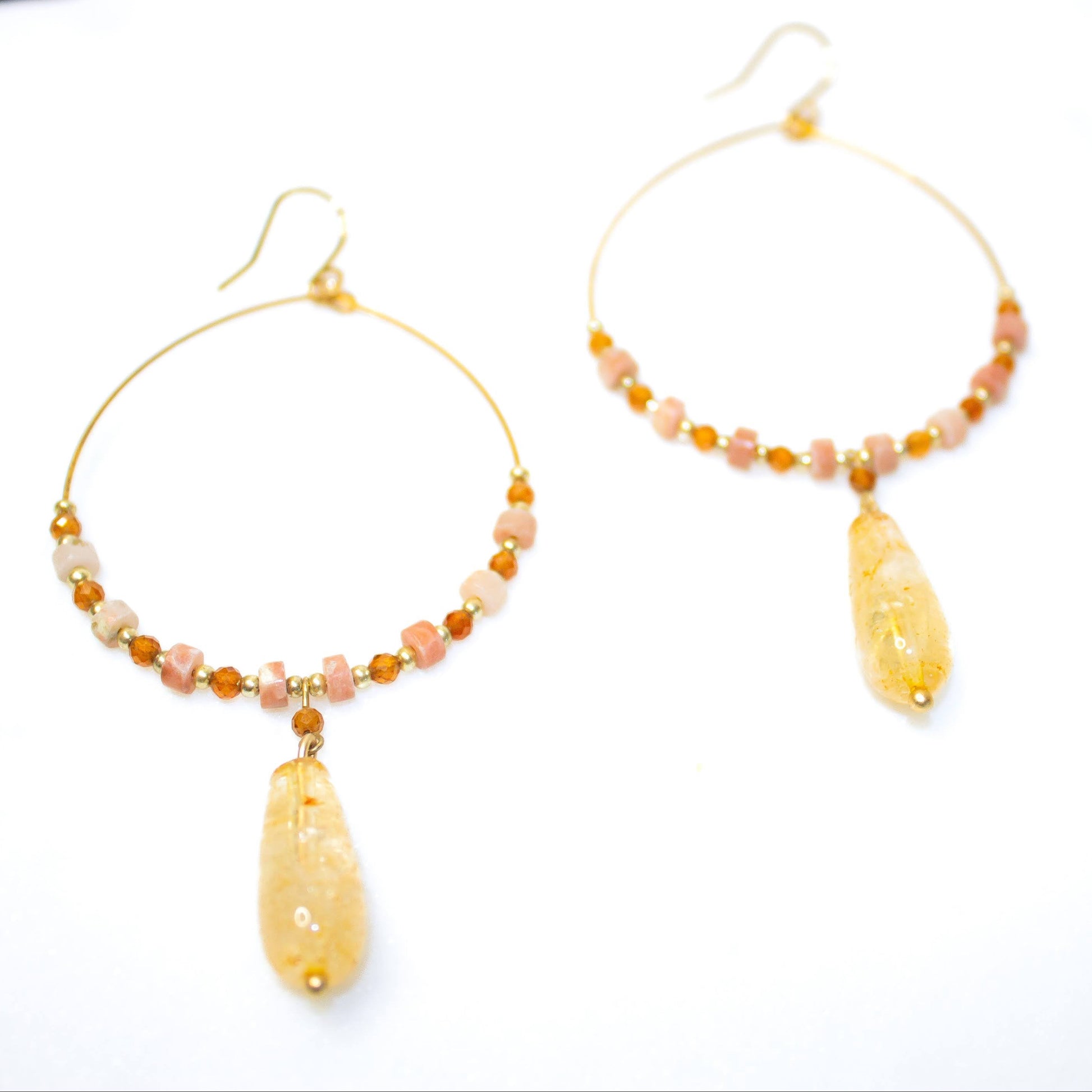 Gold hoop earrings with yellow and pink beads on a white background