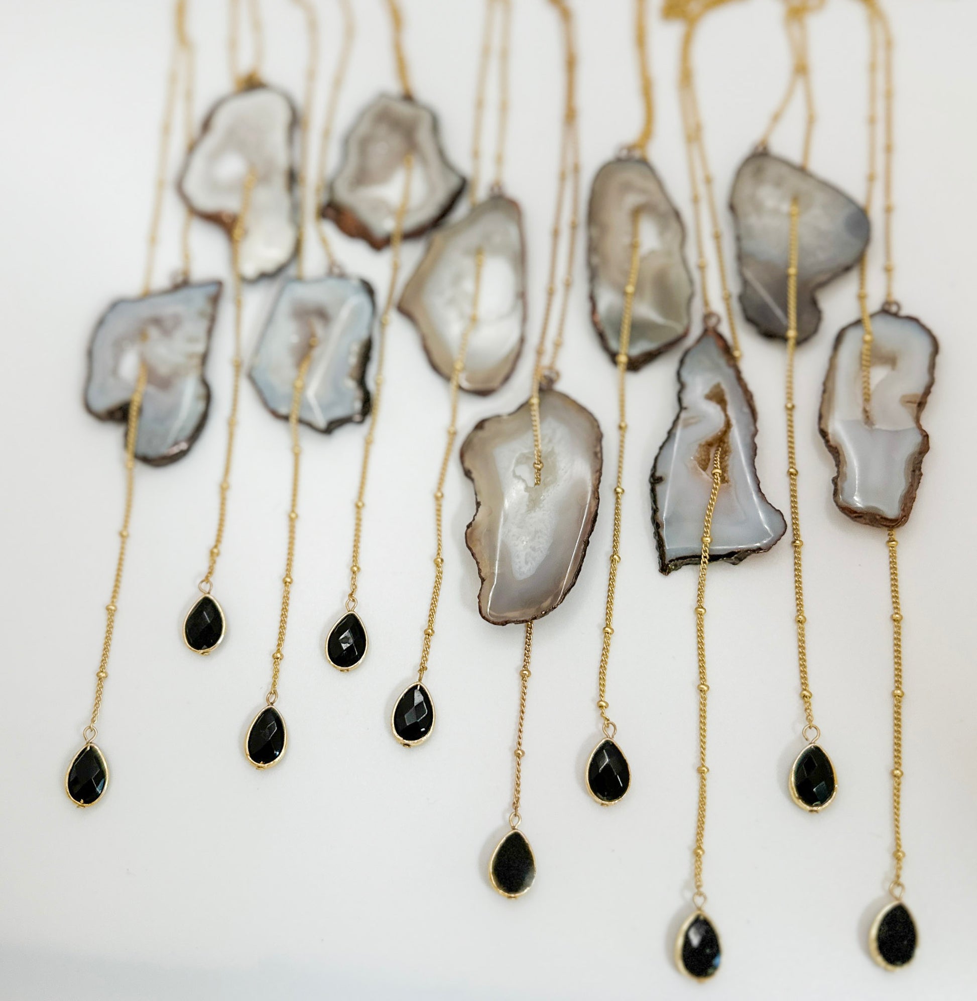 Necklaces with agate slices and black teardrop pendants on a white background