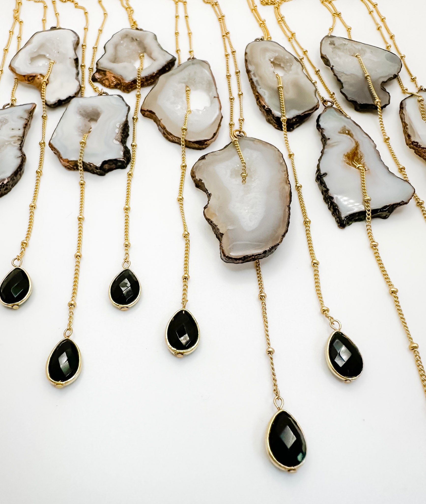 Necklaces with agate stones and black teardrop pendants on gold chains.